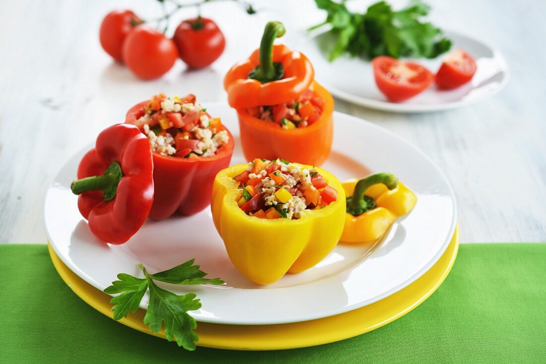 Red, yellow and orange peppers filled with a rice, pepper and tomato salad