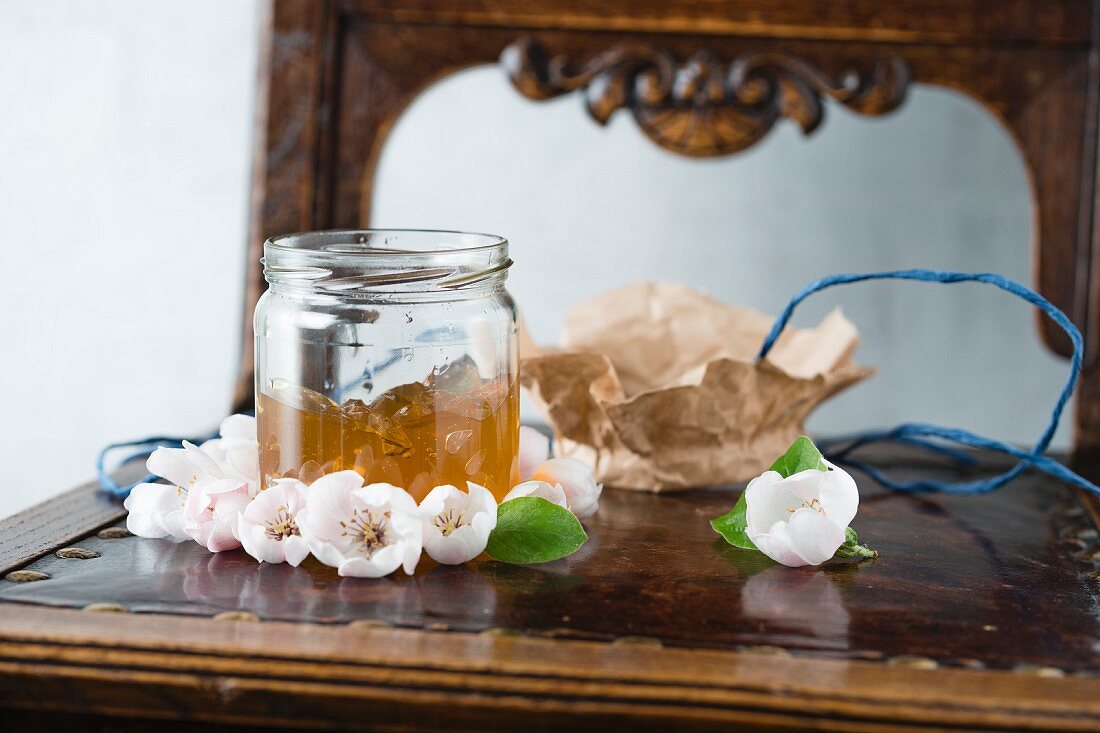 A jar of quince jelly on an antique chest of drawers with a mirror
