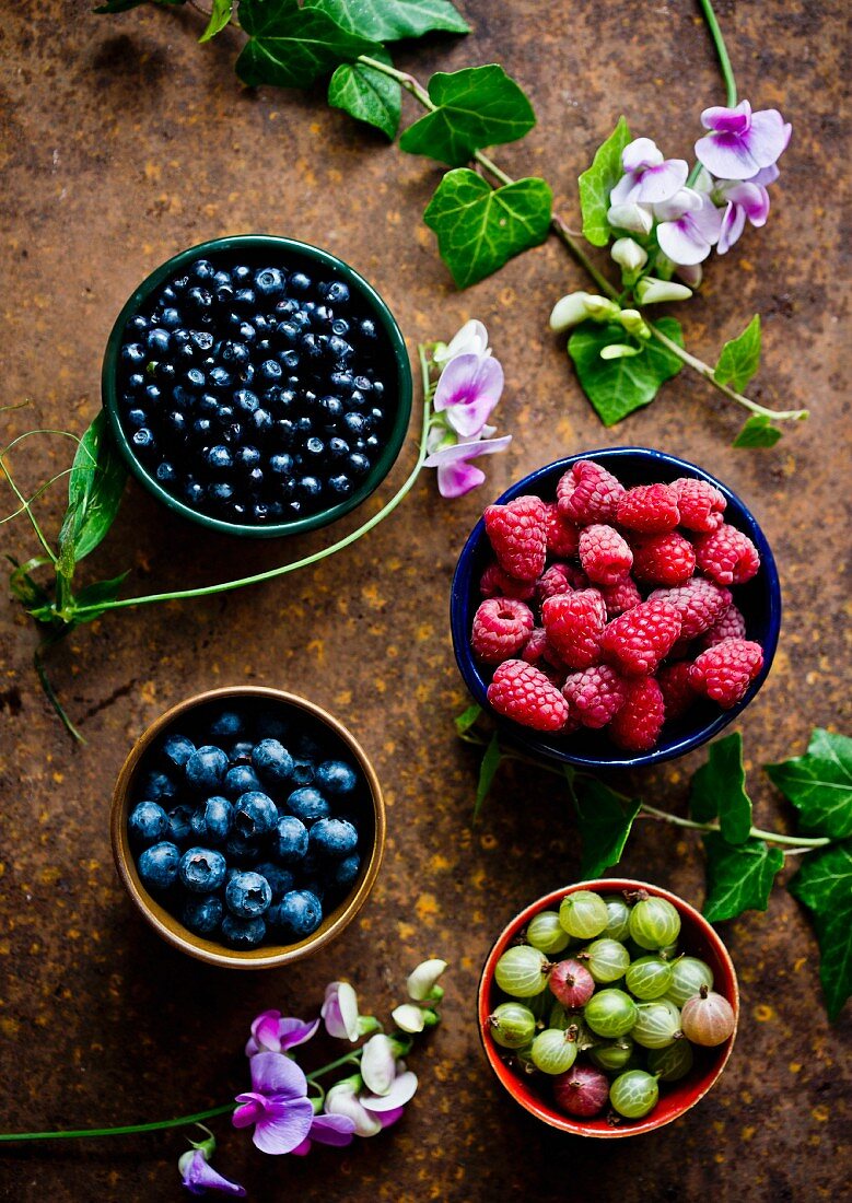 Bowls of fresh summer berries (raspberries, gooseberries and blueberries)