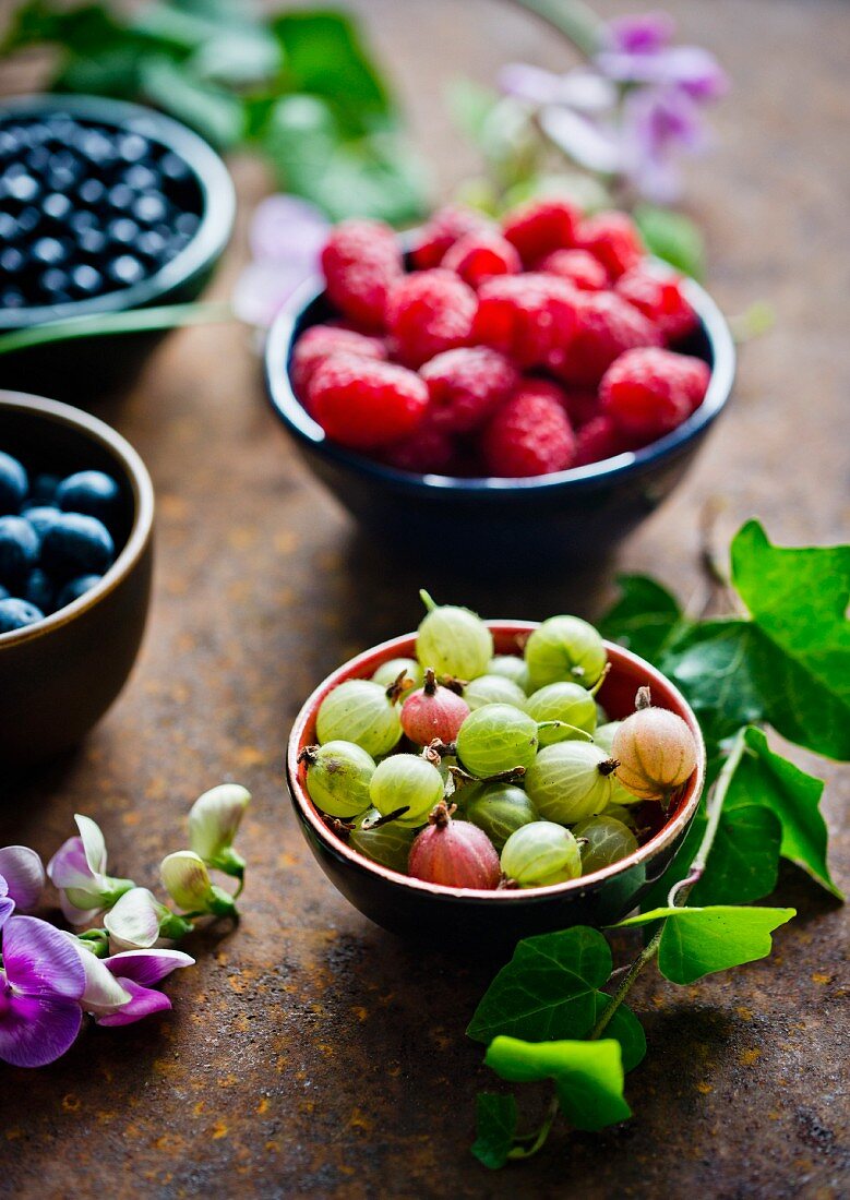Fresh gooseberries, blueberries and raspberries in bowls