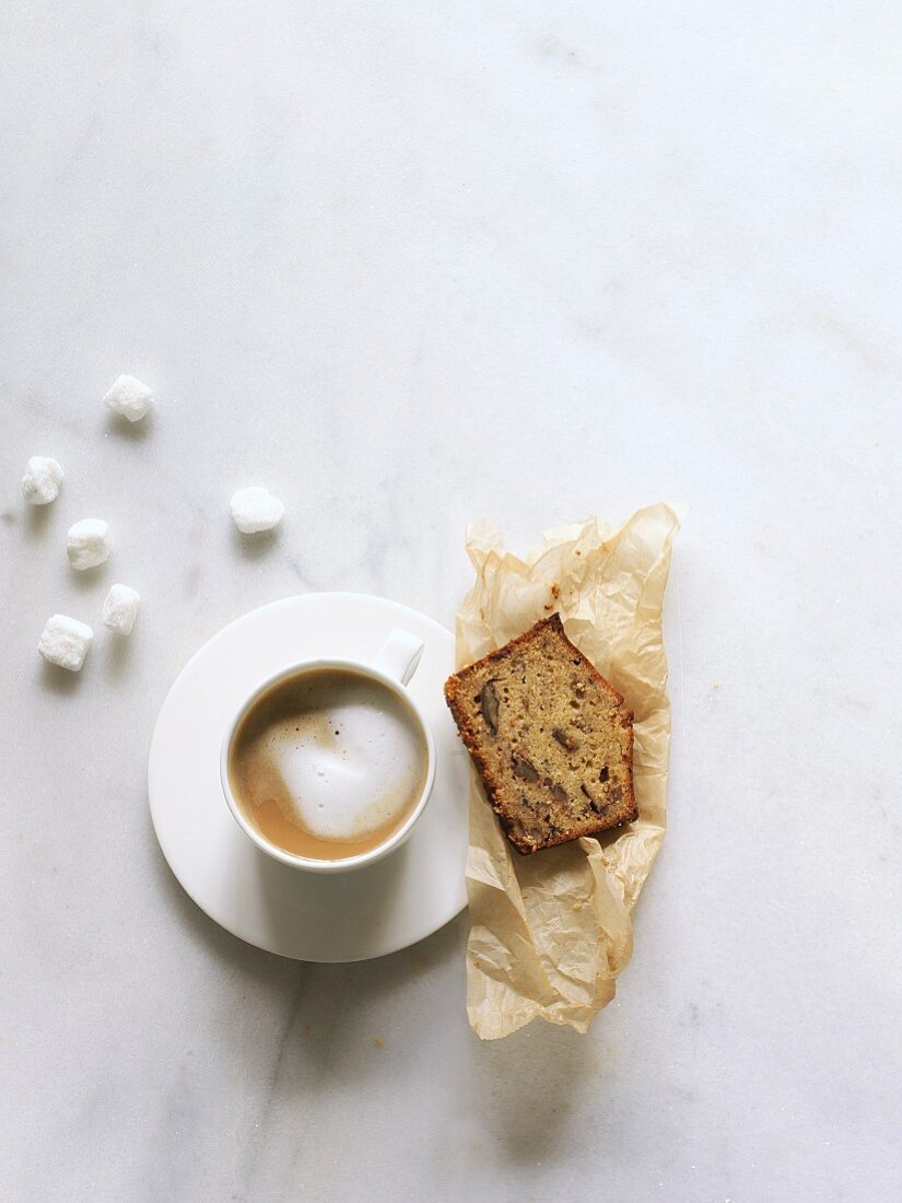 A slice of date and pecan nut cake served with a cappuccino (seen from above)