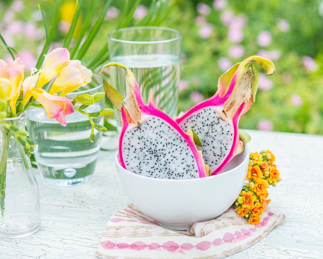 A halved pitahaya (dragon fruit) in a bowl on a garden table