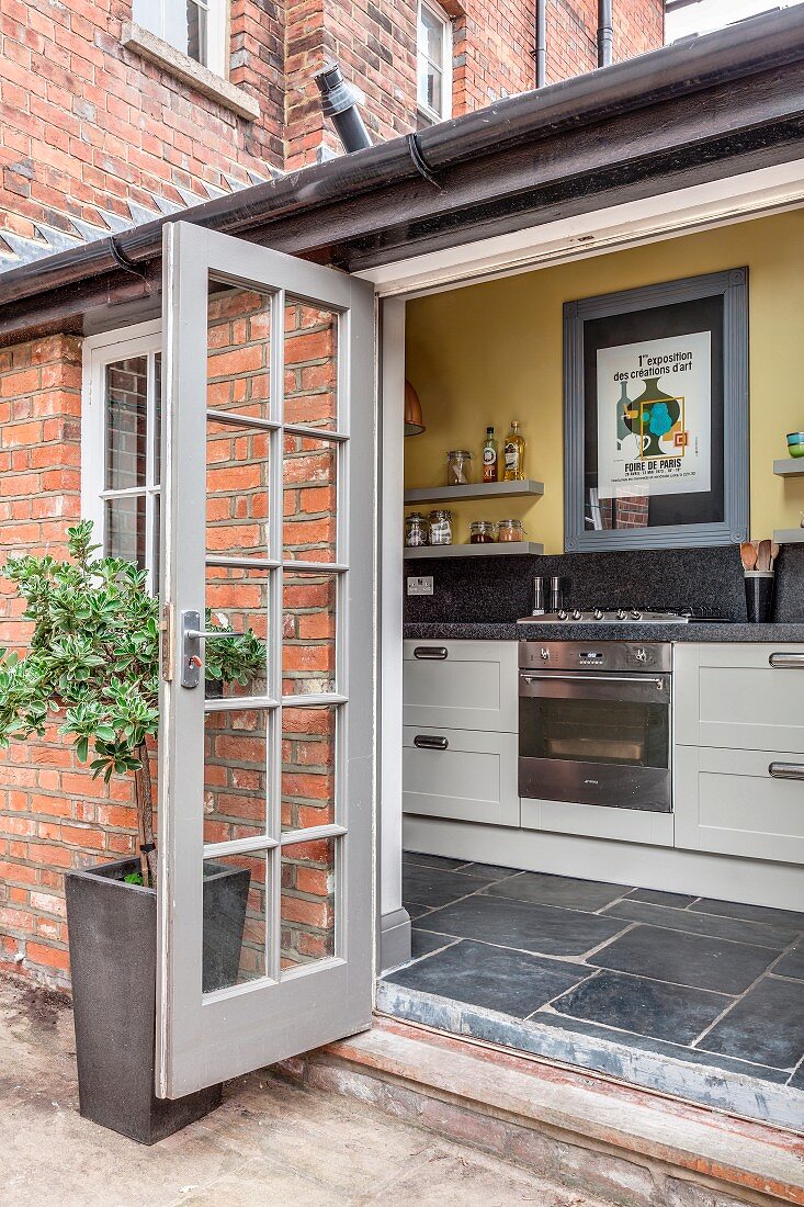 View of kitchen counter through open terrace doors in traditional brick building