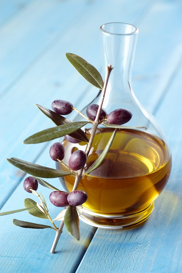 A carafe of olive oil and a sprig of olives