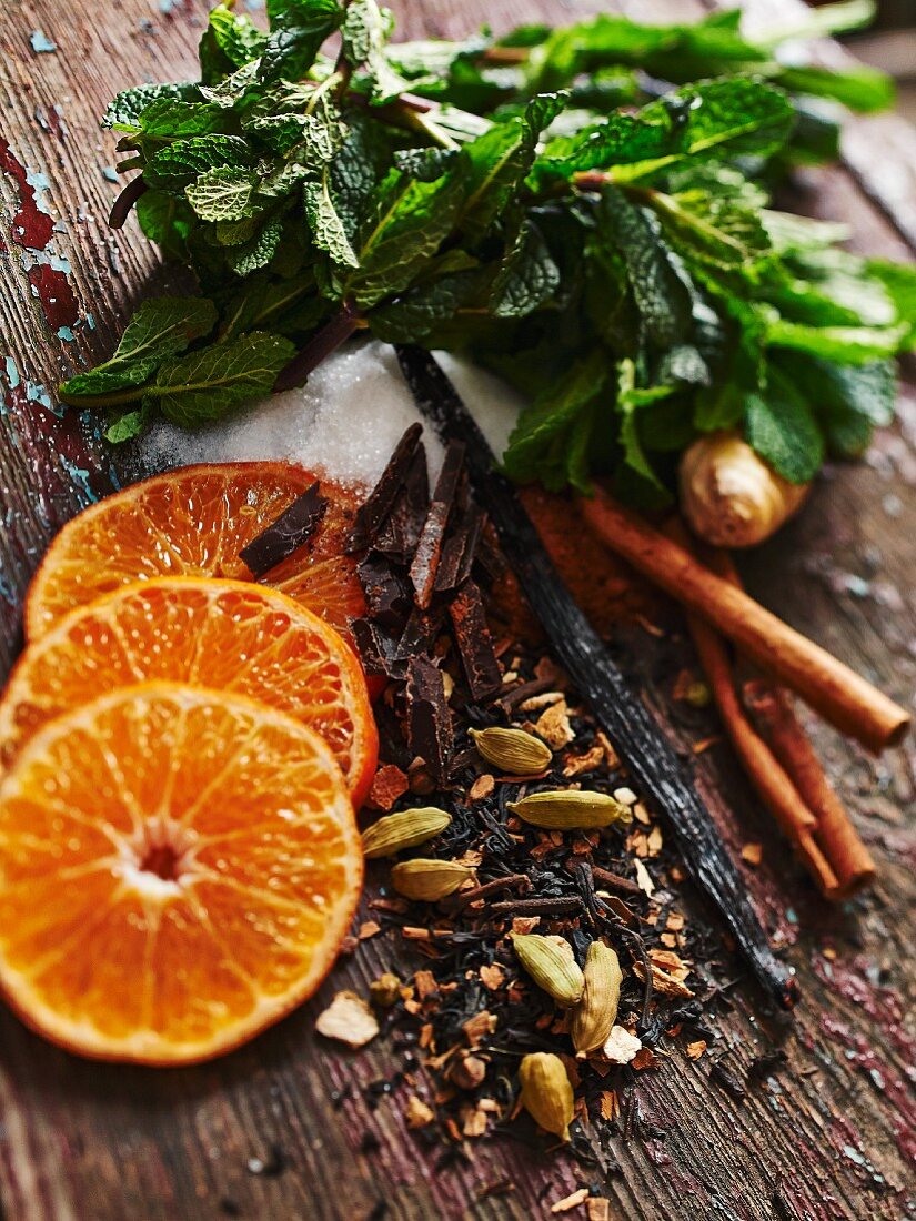 Various ingredients for hot drinks (oranges, spices, ginger, sugar, mint)