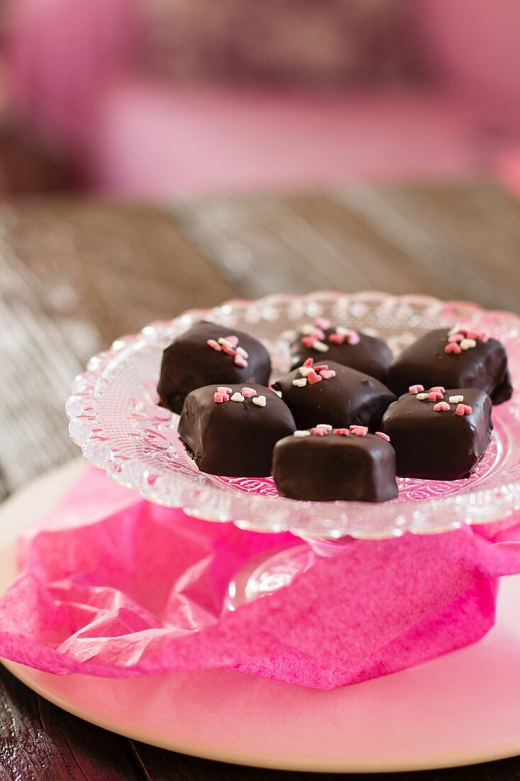 Chocolate pralines with sugar hearts on a crystal plate