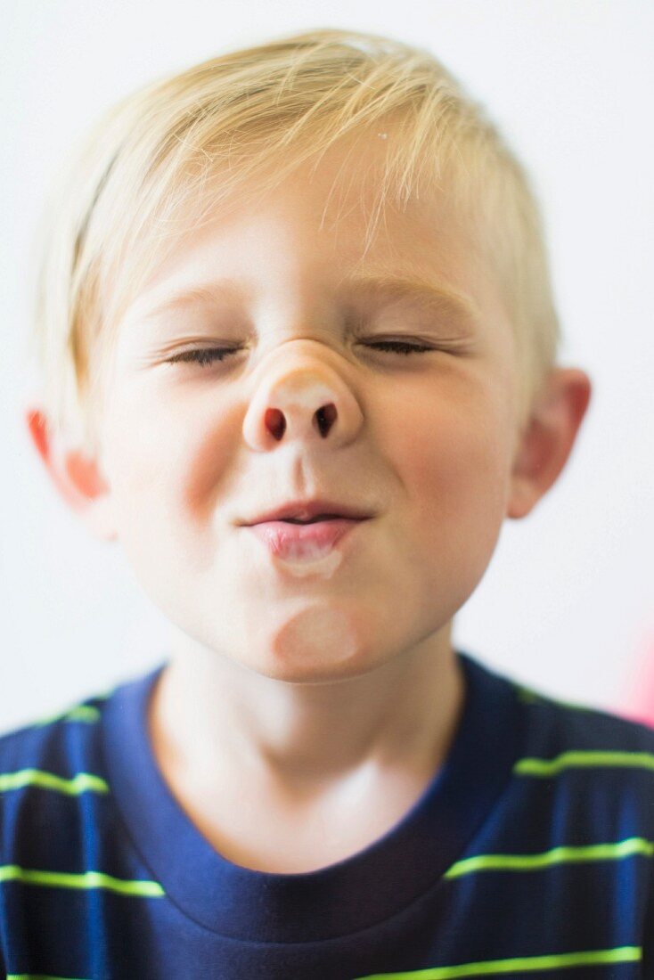 A blond boy squashing his nose against a window