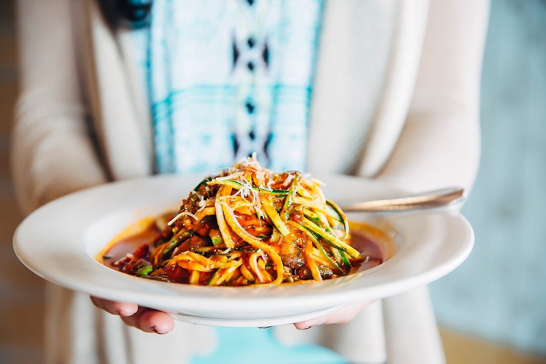 A person holding a plate of pasta