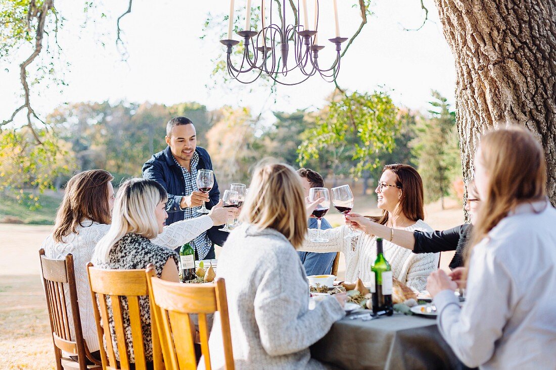 Friends raising glasses of wine outside at an autumnal decorated table