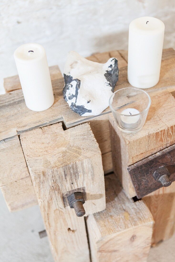 weiße Kerzen und Stein auf rustikalem Holzobjekt