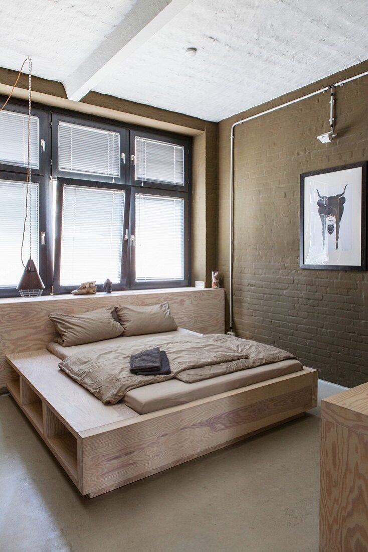 Double bed below window in minimalist beige bedroom