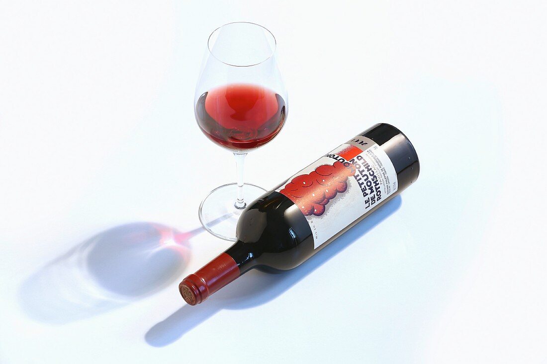 Rotwein im Glas und liegende Weinflasche