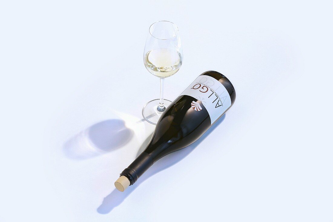 A glass of white wine and a bottle of wine lying on its side