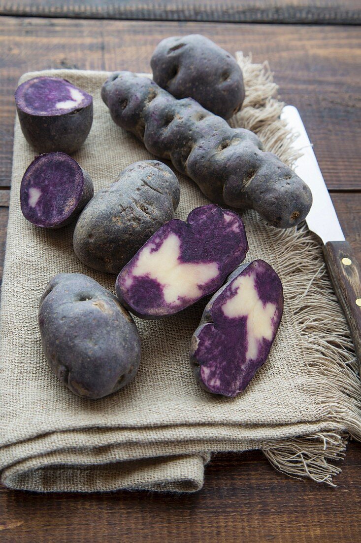 Violette Kartoffeln, ganz und halbiert auf Tuch liegend
