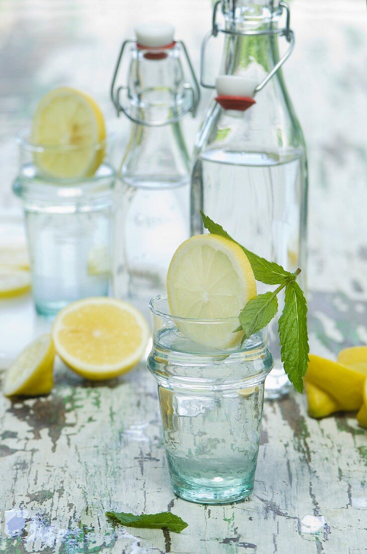 Water flavoured with lemon slices and mint in bottles and glasses