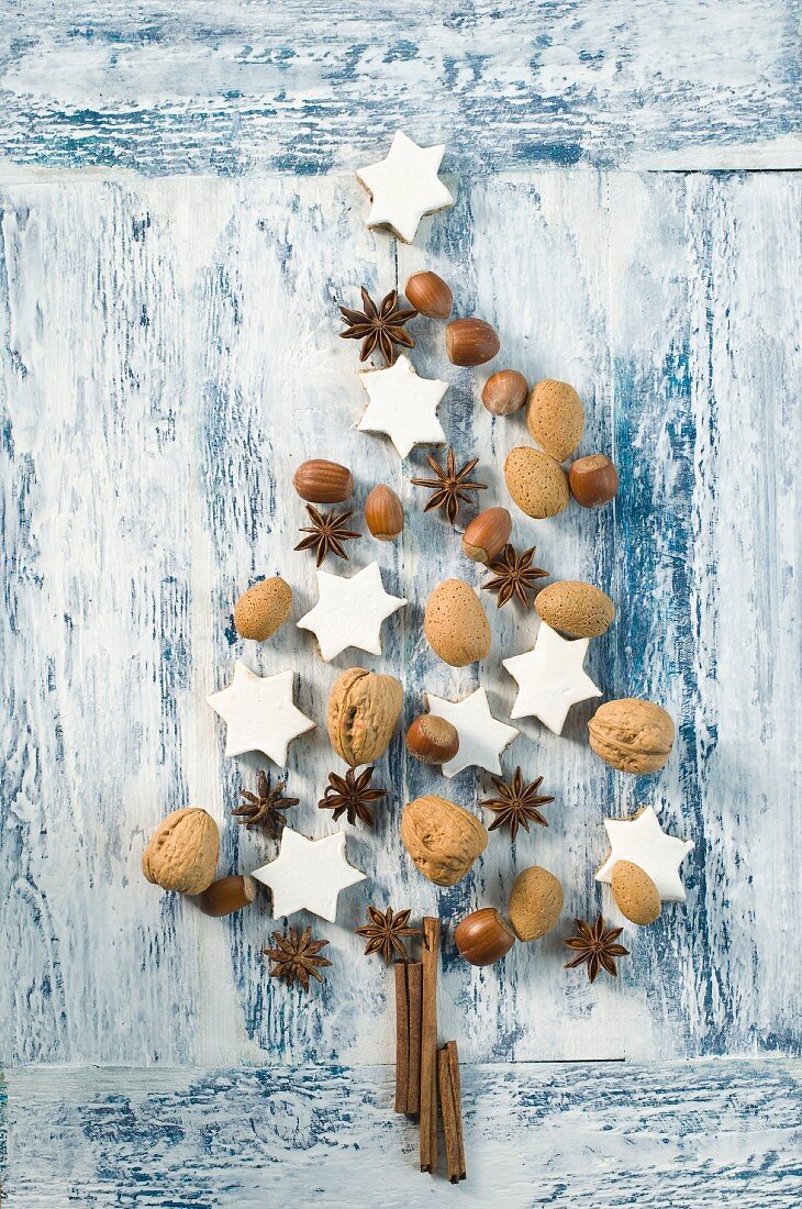 Cinnamon stars, cinnamon sticks, star anise and nuts in the shape of a Christmas tree