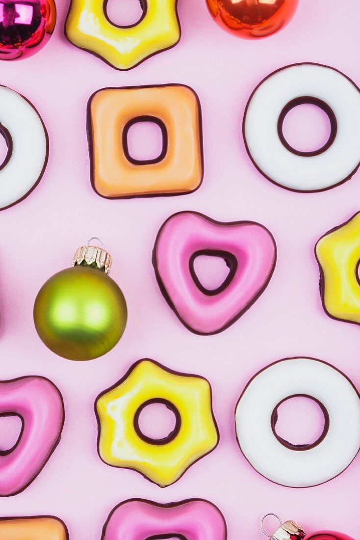 Christmas cookies and baubles on a pink surface (full frame)