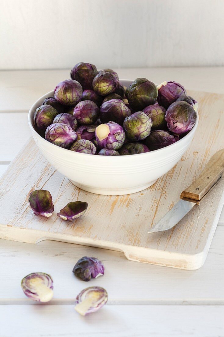 Frischer roter Rosenkohl in Schüssel auf Holzschneidebrett