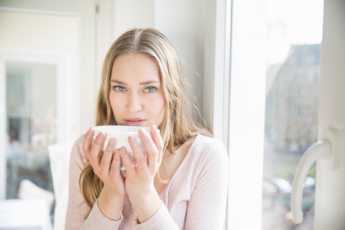A blonde woman holding a bowl of coffee