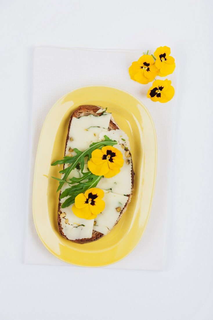 A slice of bread topped with Pecorino cheese, rocket and pansies