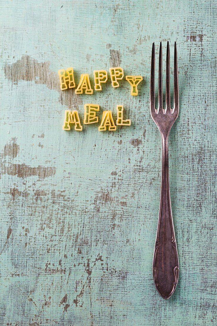 Schriftzug Happy Meal aus Buchstabennudeln, daneben Gabel