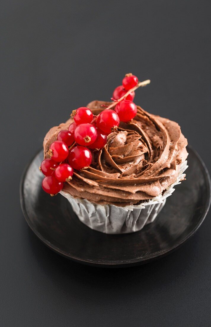 Cupcake mit Schokoladencremehaube und Johannisbeeren