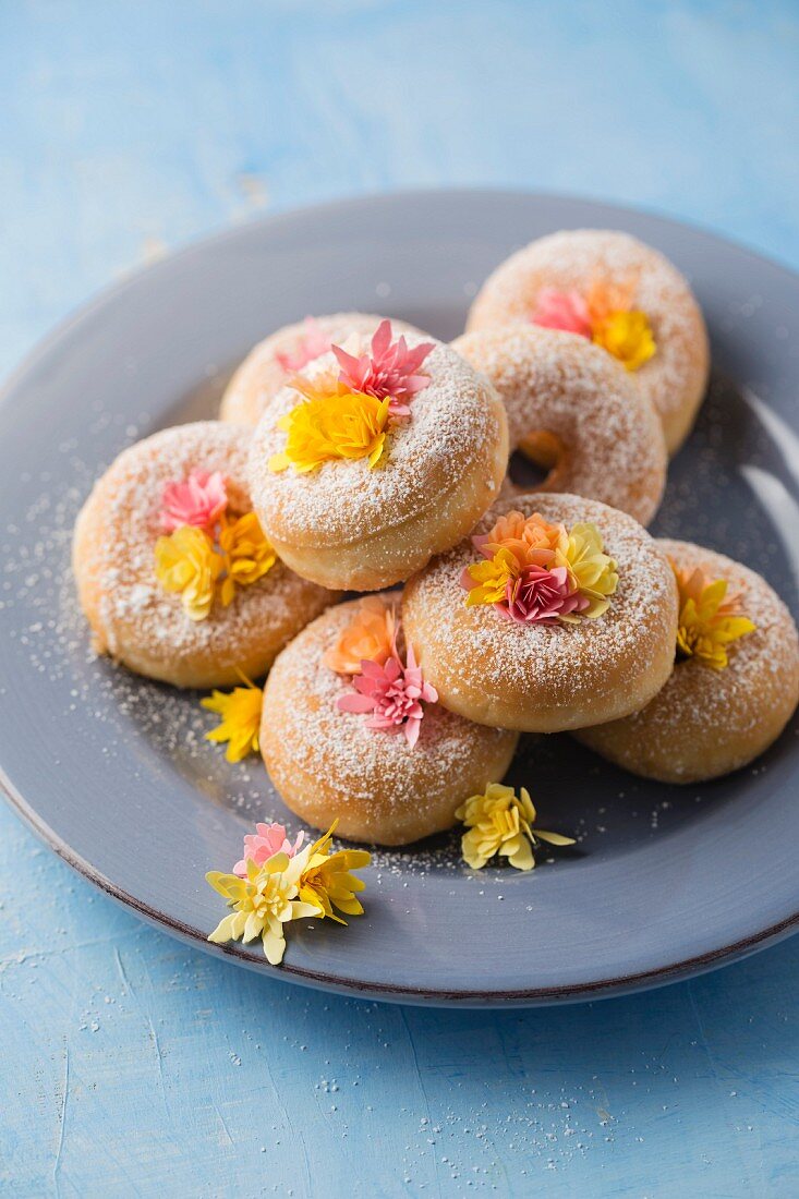 Doughnuts dekoriert mit Papierblüten auf Teller