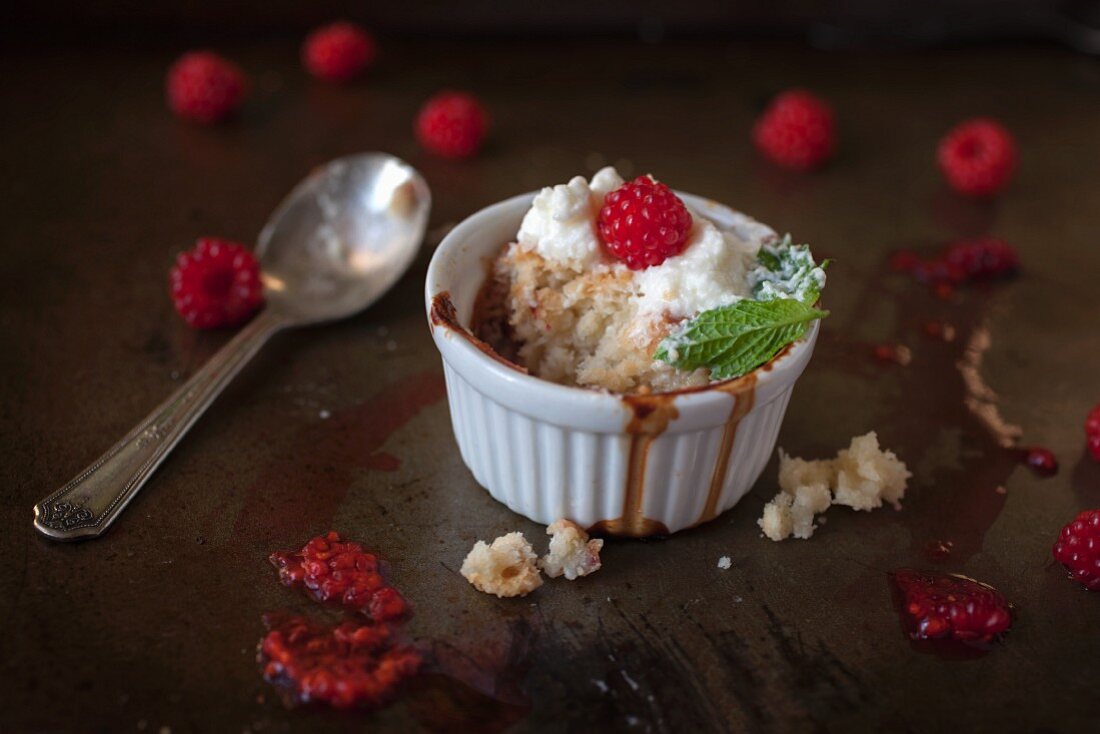 A cobbler with wild raspberries and cream with a bite taken out