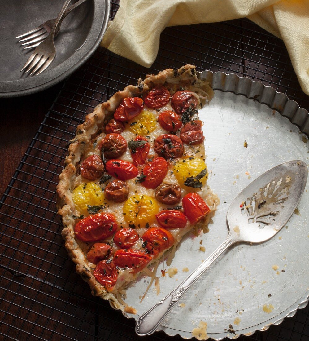 The remains of tomato tart with red and yellow tomatoes in a baking tin