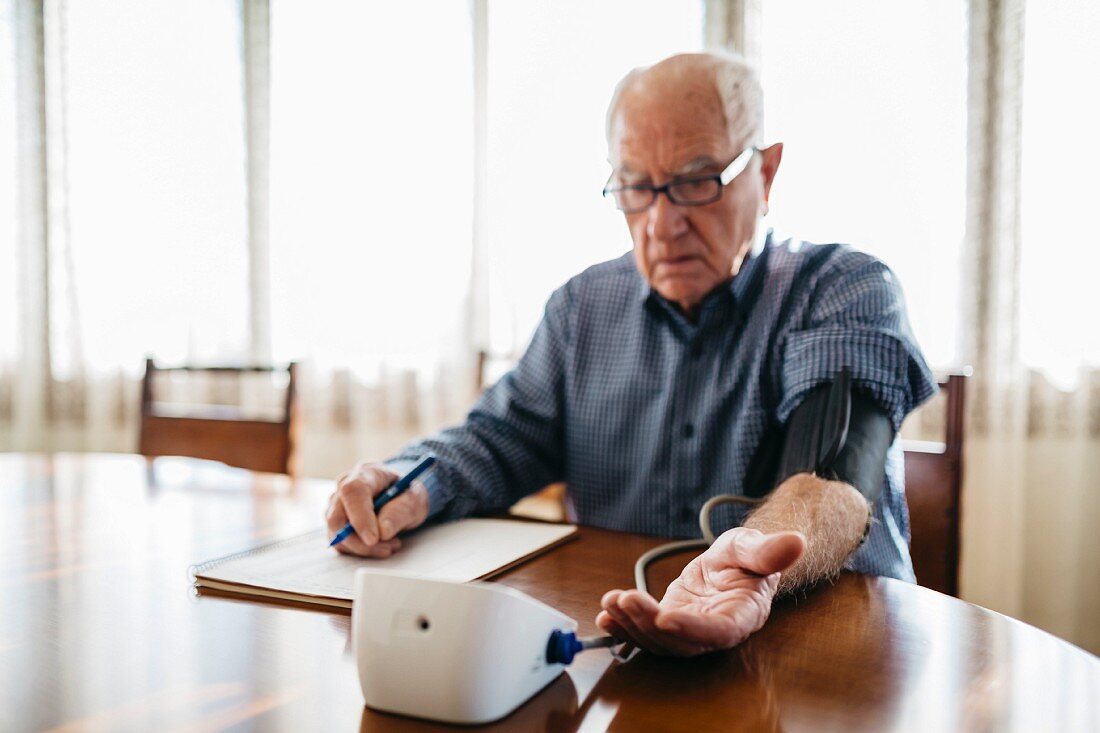 An older man measuring his blood pressure at home