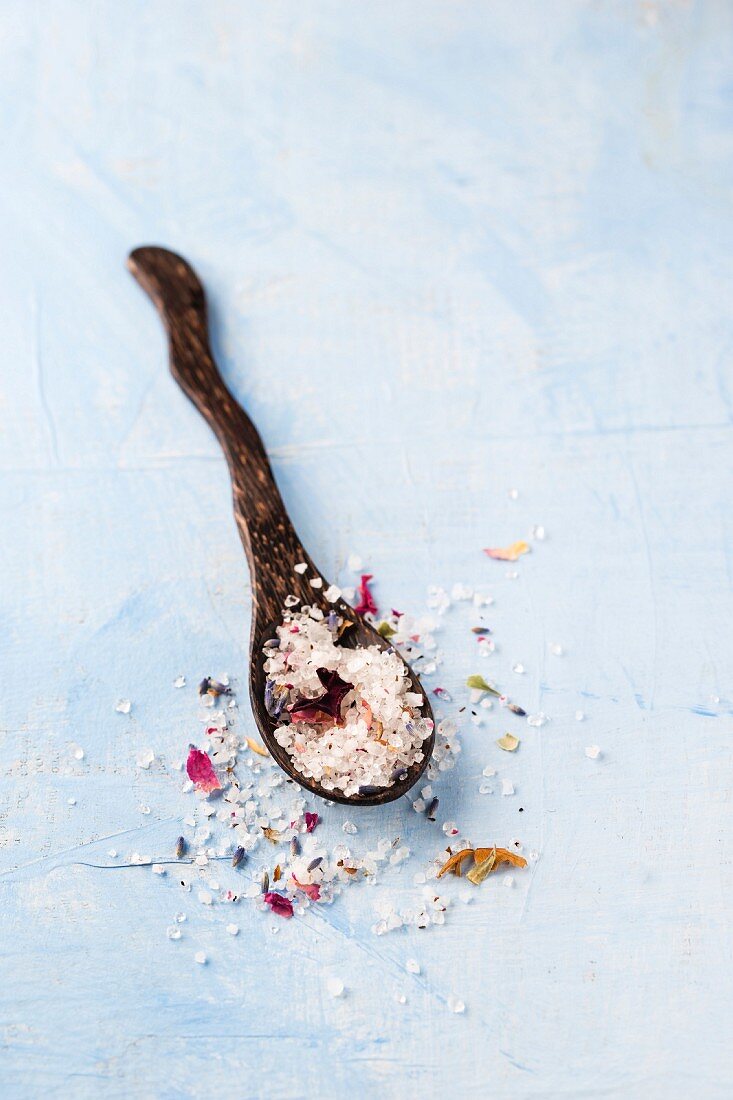 A wooden spoon with rose and lavender bath salt