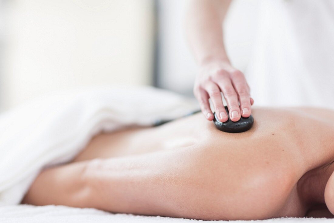 A woman having a hot stone massage in a spa