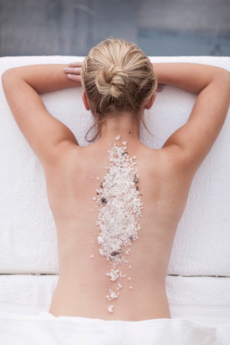 A woman with sea salt on her back in a spa