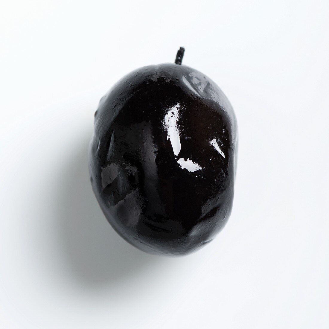 A black olive on a white surface