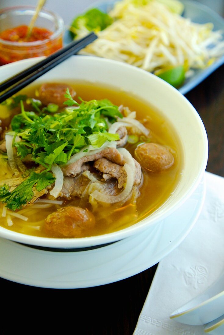 Pho Dac Biet (noodle soup, Vietnam) with beef, rice noodles, bean sprouts, limes and basil
