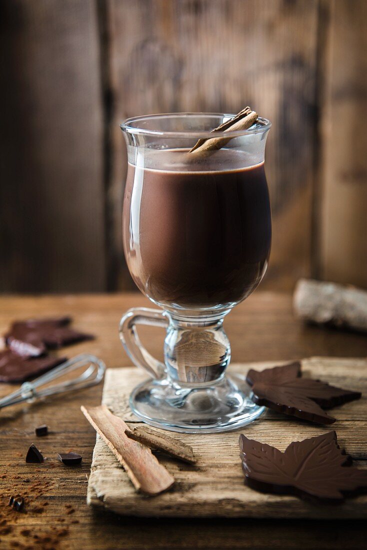 Ein Glas heiße Schokolade mit Zimt und Schokoladenblättern