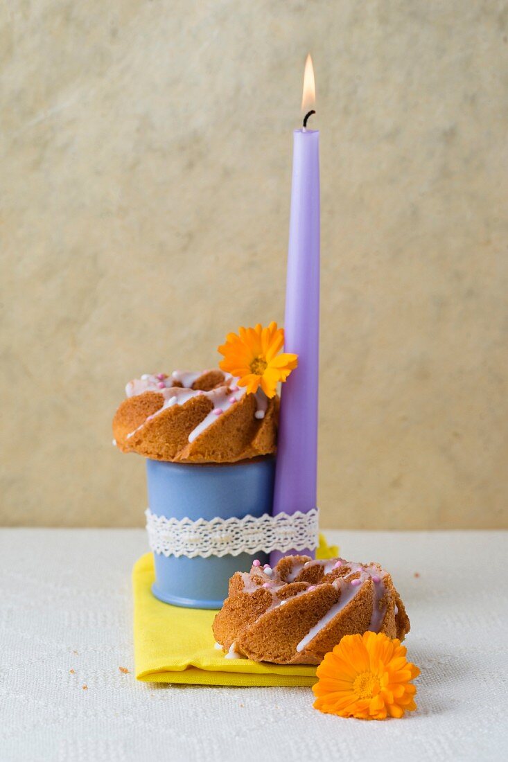 Zwei Mini-Kranzkuchen dekoriert mit brennender Kerze und Ringelblumen