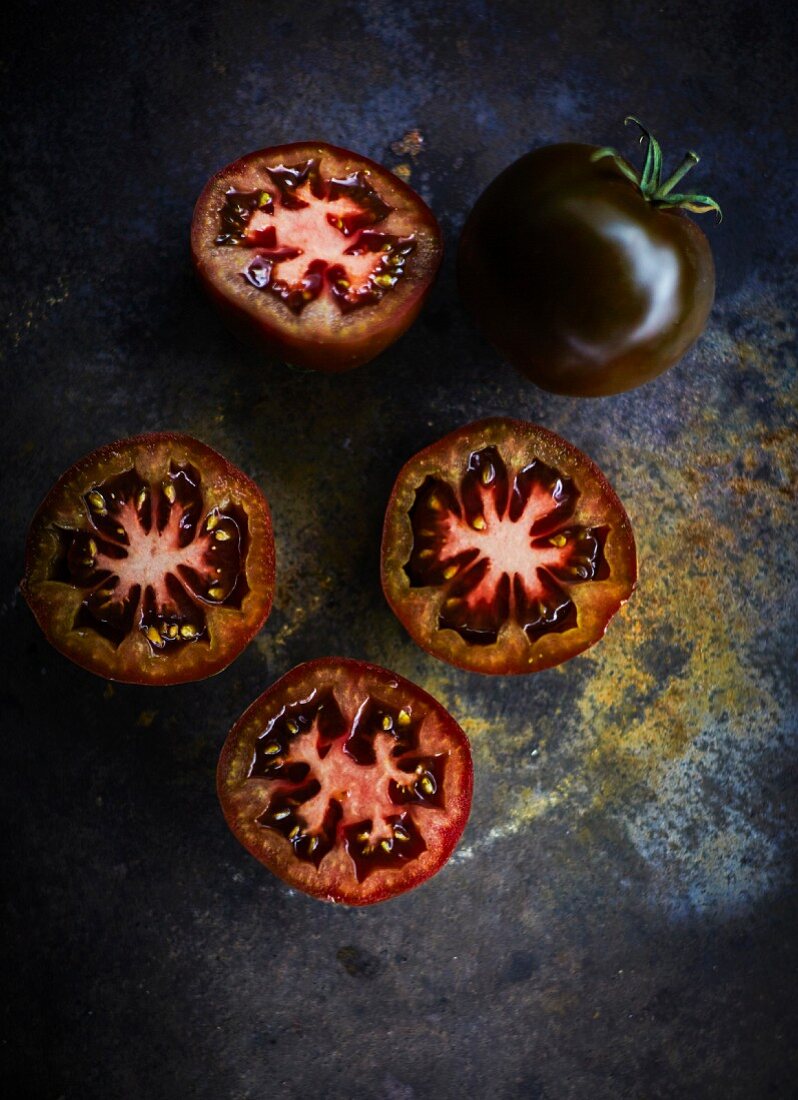 Black tomatoes, whole and halved (seen from above)