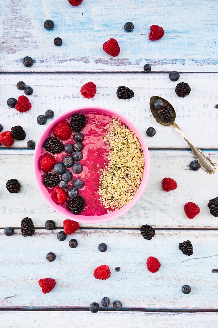 A smoothie bowl with berries and hemp seeds on a wooden surface (seen above)