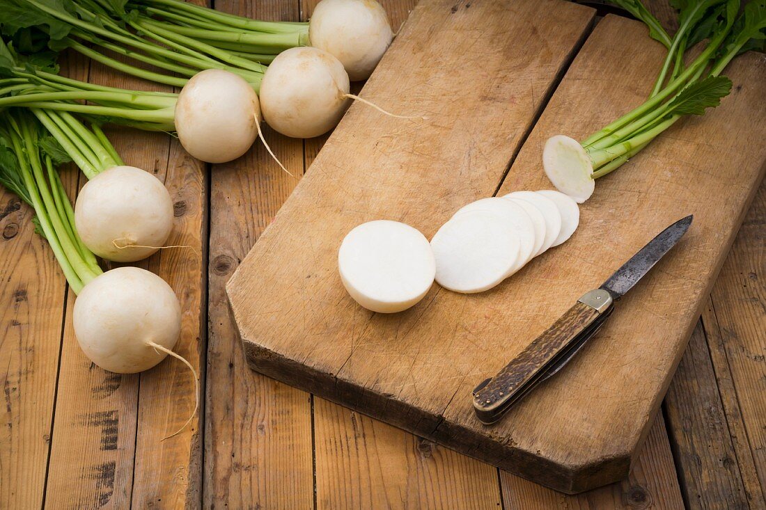 White turnips, whole and sliced, on a wooden board