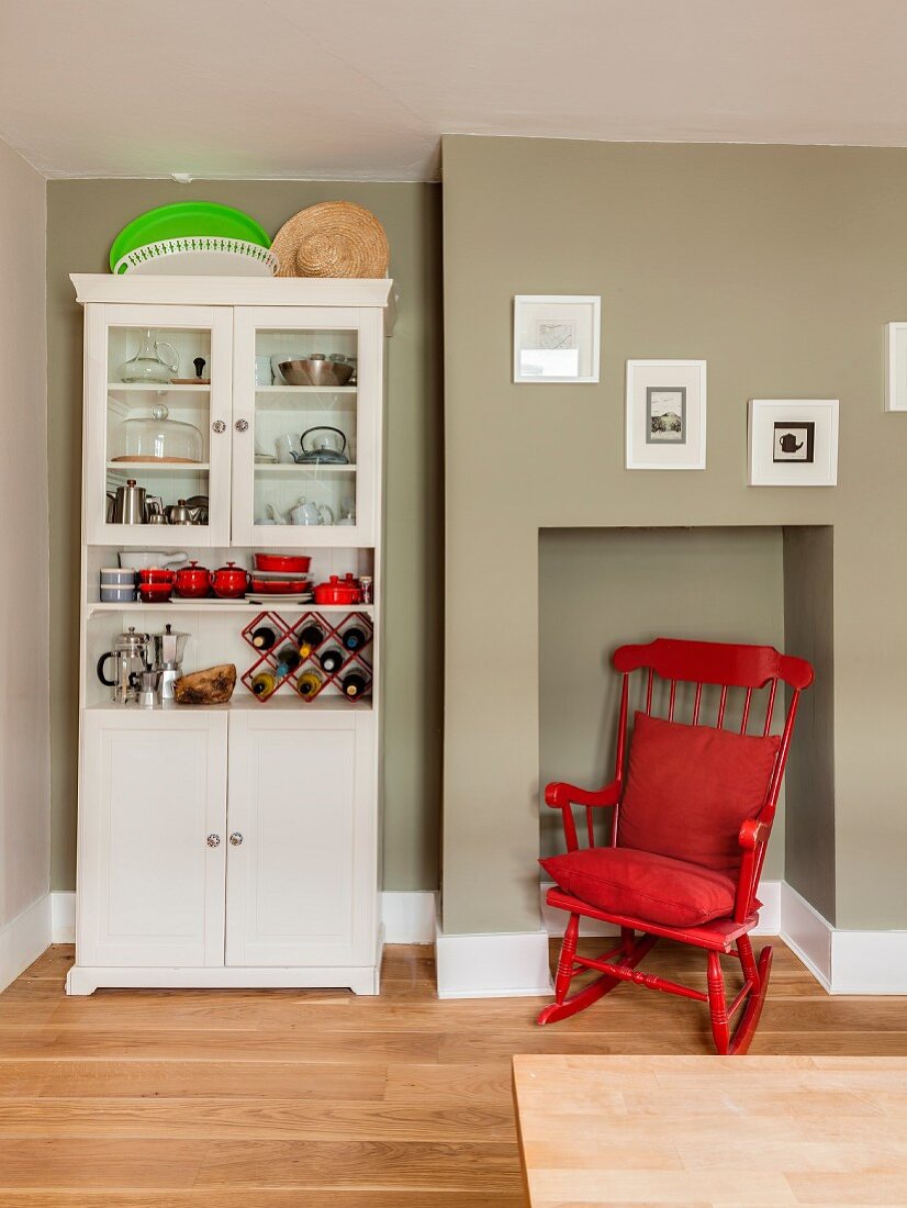 Red rocking chair in niche next to kitchen dresser