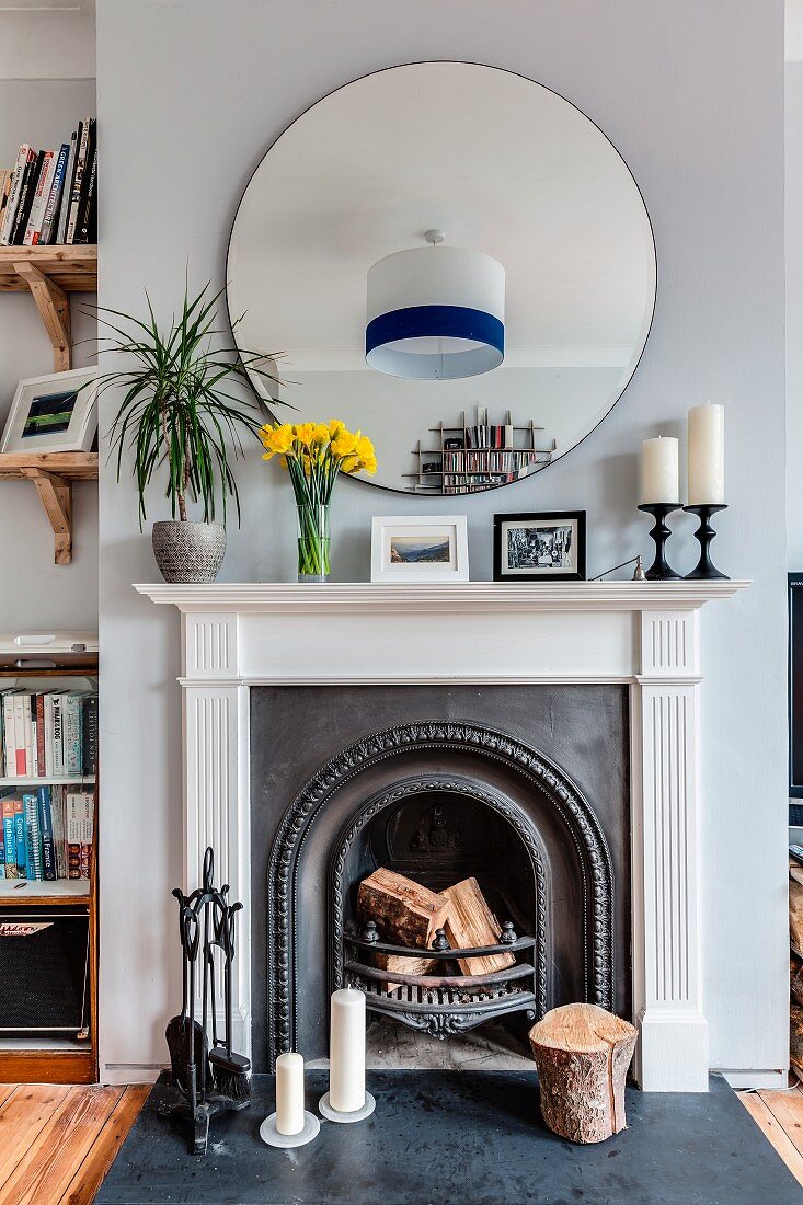 Round mirror above open fireplace with classic surround