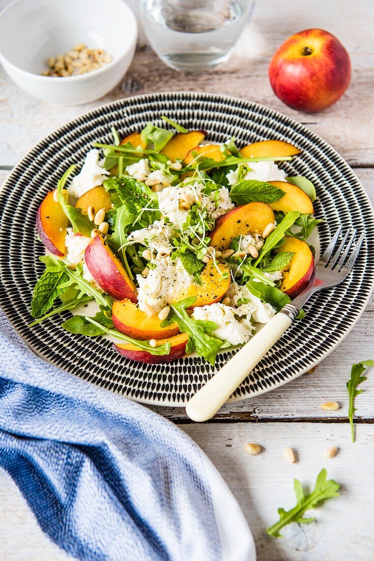 Mozzarella and nectarine salad with pine nuts and mint leaves