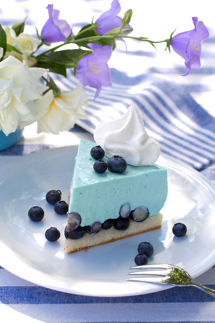 Stück Heidelbeertorte auf blau-weiß gedecktem Tisch