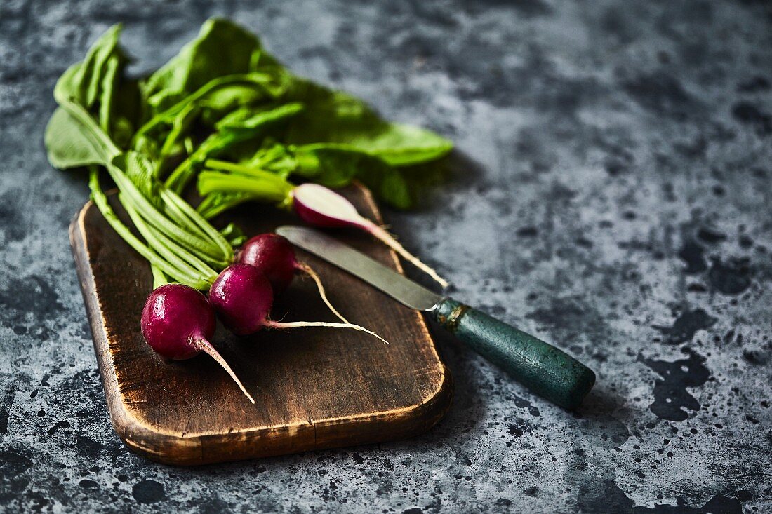 Radishes on wooden board with a knife