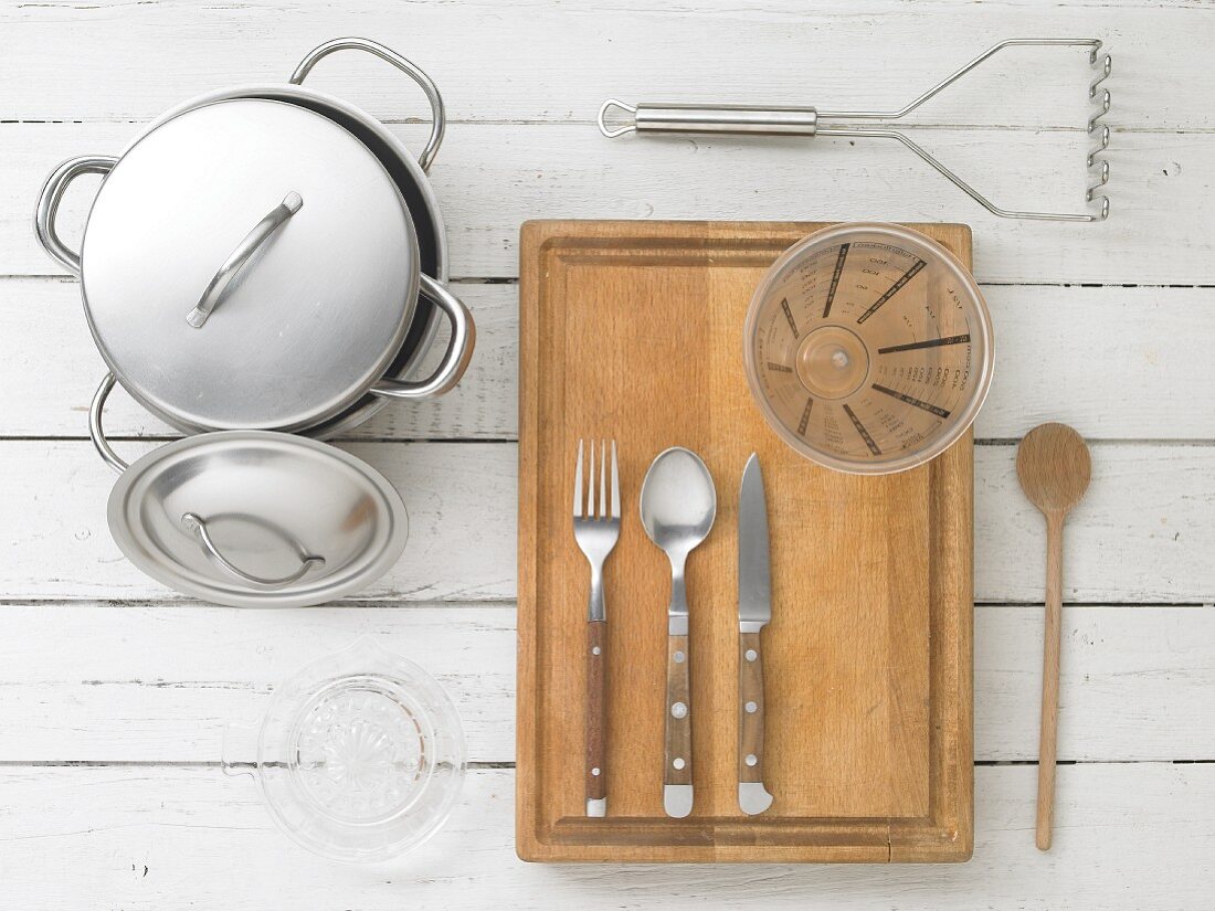 Kitchen utensils: a pot, a citrus juicer, cutlery, a measuring jug and a potato masher