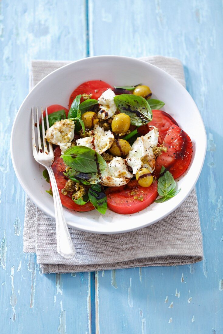 Caprese salad with buffalo mozzarella, olives and pesto