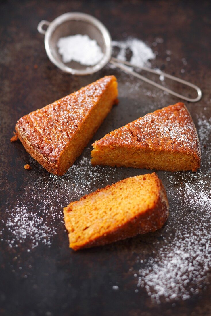 Three slices of carrot and sweet potato cake with icing sugar
