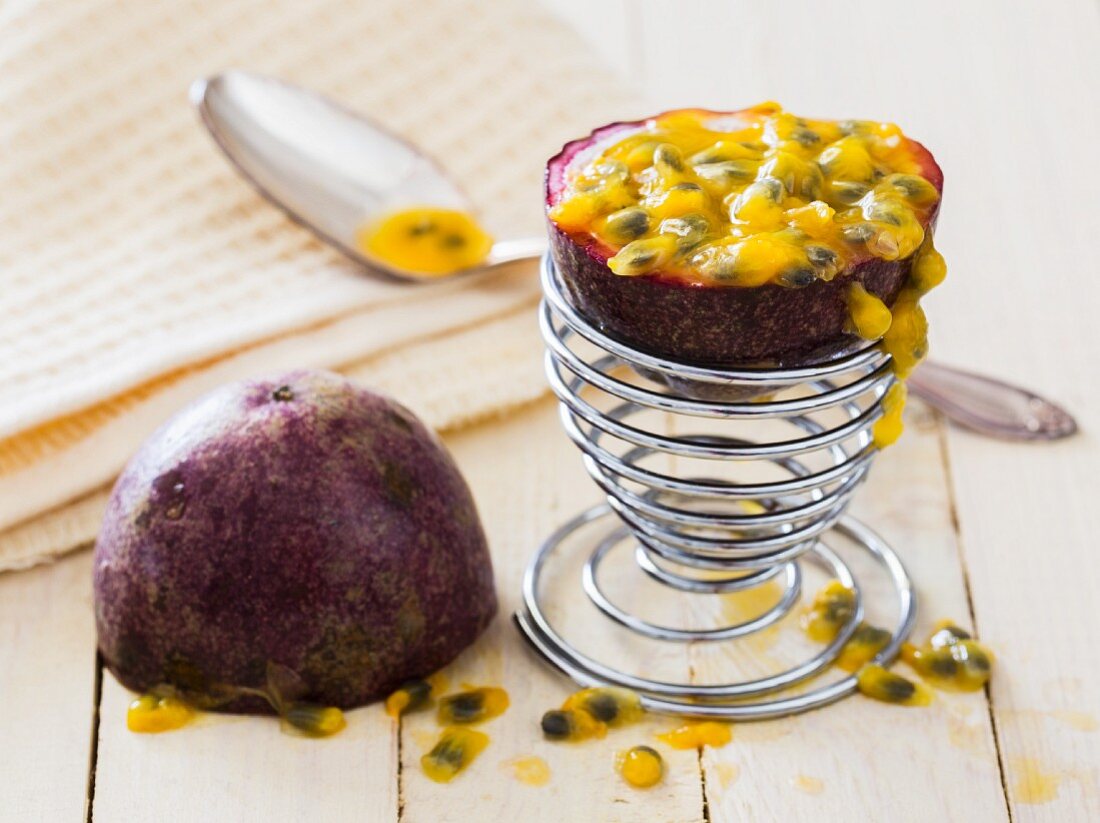 A halved passion fruit with a spoon in an egg cup