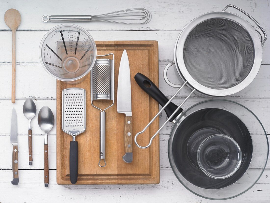 Kitchen utensils: a pan, a pot, a sieve, a grater, knives, cutlery and a measuring jug